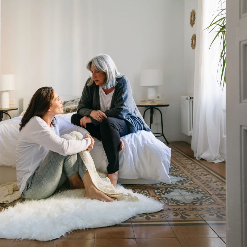 Mother And Her Daughter Talking Together On The Room At Morning.